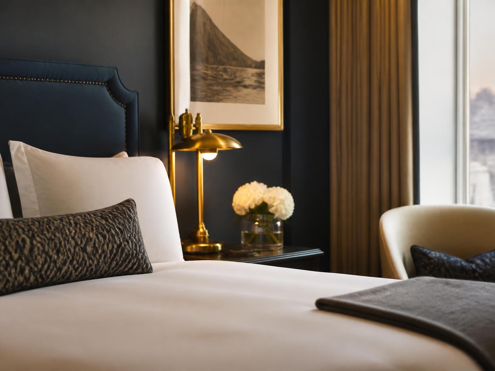 Detail of a luxury hotel guestroom with crisp white linen and a brass lamp